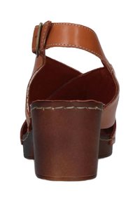 Sandalo in pelle marrone con tacco largo, cinturino regolabile e design incrociato. Presenta cuciture visibili e una texture liscia.