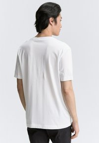 Hvid bomulds T-shirt med korte ærmer, rund hals og en afslappet pasform. Glat tekstur, ingen synlige grafikker eller mønstre.