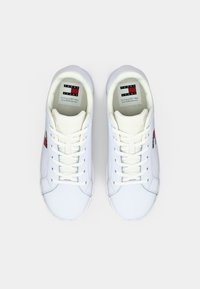 Weiße Ledersneaker mit Schnürung, kontrastierenden roten und blauen Logoakzenten, runder Zehenpartie und strukturiertem Gummisohle.