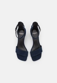 Mörkblå mocka högklackade sandaler med ankelsnöre, bred framrem och en slät svart innersula. Justerbar metallspänne.