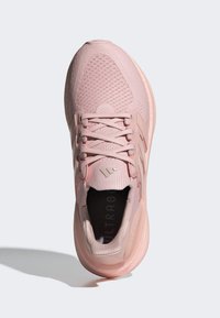 Rosa idrettssko med teksturert strikkeoverdel, snøring og Ultraboost-merke. Rund tå og polstret såle for komfort.