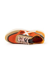 Sneaker arancione con accenti beige, dotata di un logo in bianco e nero, tessuto testurizzato e lacci bianchi a contrasto su una suola ammortizzata.