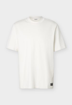 Jednoduché bílé tričko s krátkými rukávy, kulatým výstřihem a malou černou obdélníkovou značkou blízko spodního lemu.