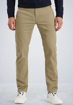 Chinos en coton beige avec une coupe slim, dotés de passants de ceinture et de poches avant, associés à des baskets blanches et un sweat-shirt navy.