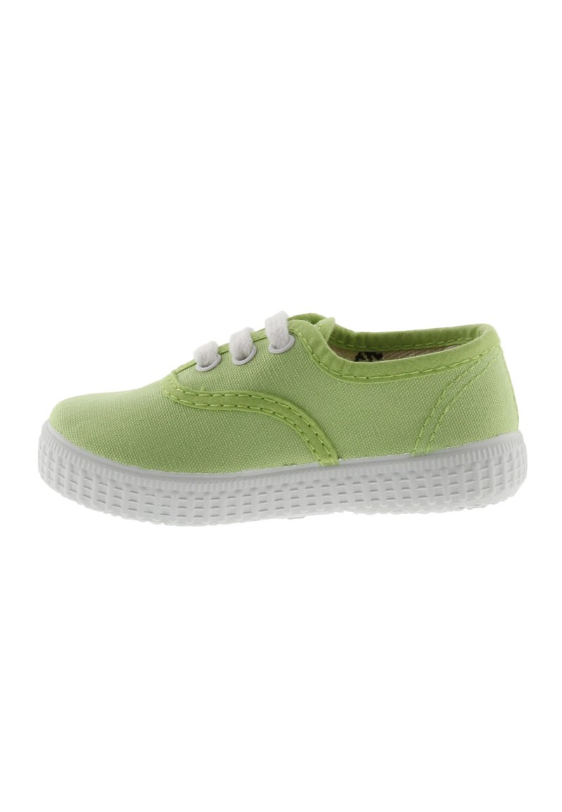 Zapatilla de lona verde claro con suela de goma blanca, tres ojales blancos y costuras en contraste a lo largo del costado. Diseño de caña baja, textura mínima.