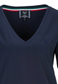 Navyblauwe V-hals T-shirt met korte mouwen, getextureerde stof, inclusief een logo-accent en een gestreepte kraag in groen, wit en rood.