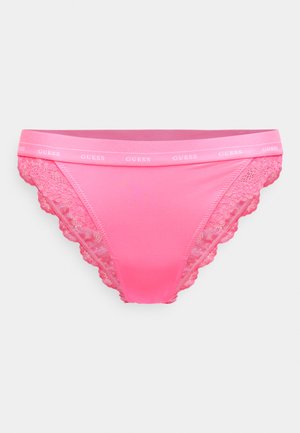 Rozā mežģīņu apakšbiksītes ar gludu, elastīgu jostasvietu un "GUESS" logotipu, izceļot viļņotu malu un seksīgu dizainu.