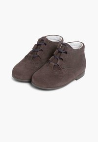 Botas de tobillo de ante marrón con un diseño de borde, que cuentan con cordones oscuros y una punta redondeada. Suela plana de goma, forro interior blanco.