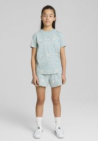 Ensemble assorti bleu clair composé d'un t-shirt à manches courtes et d'un short avec un motif floral. Fabriqué en tissu lisse, il présente un design décontracté.