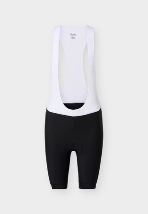 Jalgratturi bikiinipüksid mustade polsterdatud lühikeste pükstega ja valgete varrukateta ülemiste rihmadega, laialt laotatult heledal taustal.