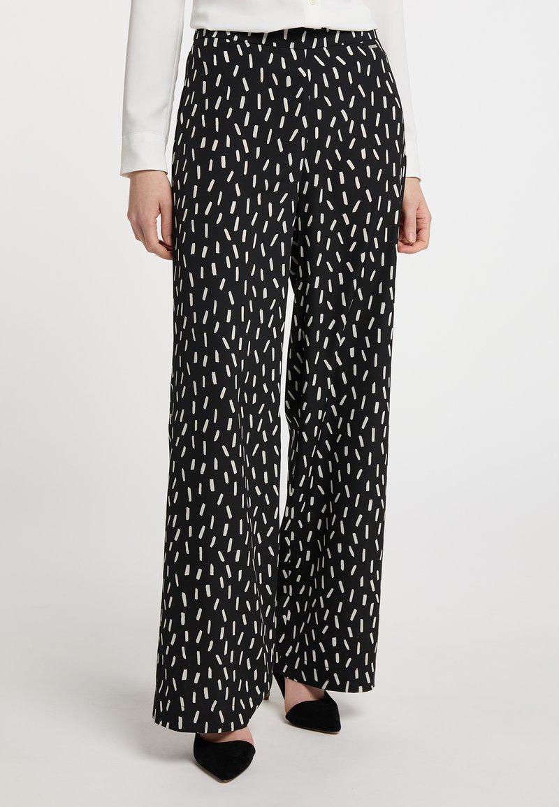 Zwarte wijde broek met een wit abstract patroon. Beschikt over een soepele stoftextuur en een relaxte pasvorm, onderdeel van een modern ontwerp.