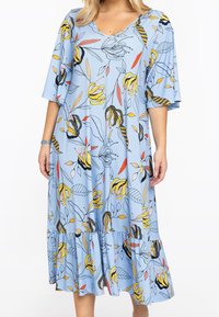 Světle modré šaty s květinovým potiskem, který má žluté a černé akcenty, s výstřihem do V, krátkými rukávy a naskládaným volánovým lemem. Vyrobeno z měkké tkaniny.