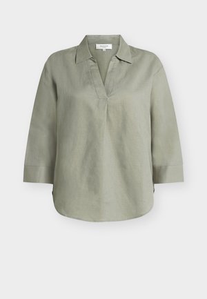 Lekka lniana bluzka w kolorze oliwkowej zieleni, z rękawami do łokcia, otwartym kołnierzem w kształcie litery V i zaokrąglonym dołem.