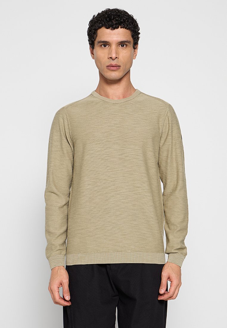 Lichtbeige trui met lange mouwen, een ronde hals, geribbelde manchetten en zoom. De textuur oogt zacht met een subtiel horizontaal patroon.