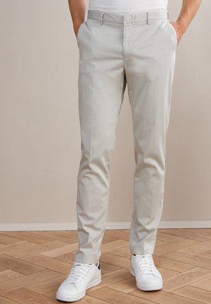 Hellgraue Chinos mit einer glatten Textur, ausgestattet mit zwei Seitentaschen und einem geraden Beindesign, kombiniert mit weißen Sneakers.