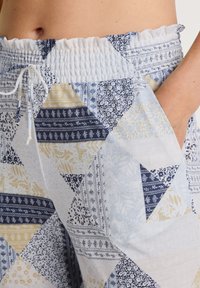 Lichte, gestreepte broek met een mix van blauwe, gele en witte vlekken. Geribbelde tailleband met trekkoord en zijzakken.