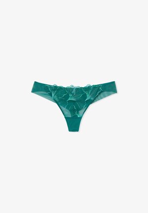 Tanga de malla color teal con bordados florales en tonos más claros, con un borde de encaje en forma de ondas y un acabado suave en la cinturilla y los laterales.