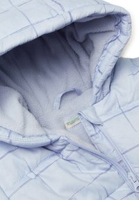 Světle modrá bunda s kapucí, která má měkkou fleece podšívku a mřížkovaný vzor. Obsahuje přední zip a štítek uvnitř s názvem značky.