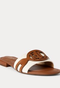 Sandal med slide-design, brunt læderrem og hvidt canvas-overdel, med et stort udskåret logo og en flad, tekstureret sål.