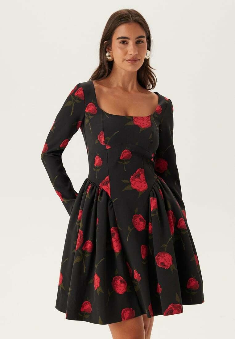 Abito nero con maniche lunghe, scollo quadrato e gonna arricciata. Presenta un motivo di rose rosse e foglie verdi in tutto il capo.