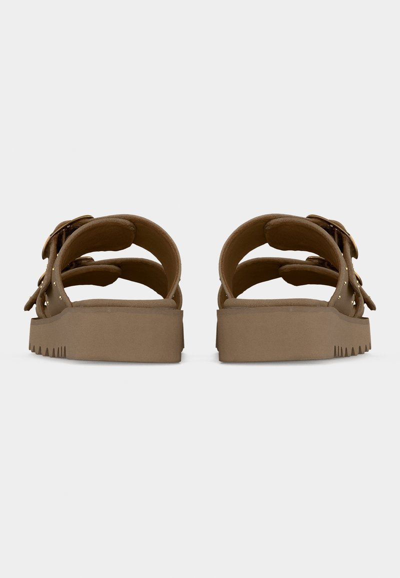 Sandales marron à bout ouvert avec des semelles épaisses, deux sangles réglables avec boucles et une semelle crantée visible de l’arrière.