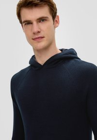 Navyblaue, strukturierte Kapuzenjacke mit weitem Hals, geripptem Stoff und Raglanärmeln, ausgestattet mit einer Kordelzugkapuze und einer taillierten Silhouette.