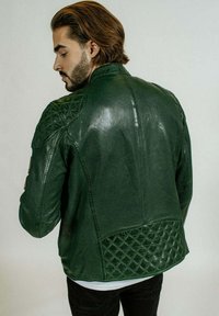 Veste en cuir vert avec un design matelassé aux épaules et dans le dos. Texture lisse et coupe ajustée, présentant un accent à motif contrasté à l'ourlet.