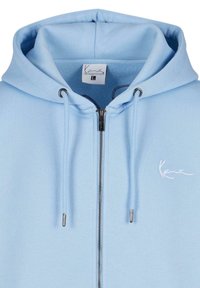 Sweat à capuche bleu clair zippé avec cordons, fermeture éclair argentée et petit logo blanc sur la poitrine gauche, taille large.