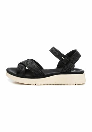 Sandalias negras con correas trenzadas, suela acolchada y hebilla ajustable en el tobillo, con una entresuela blanca y detalles texturizados.
