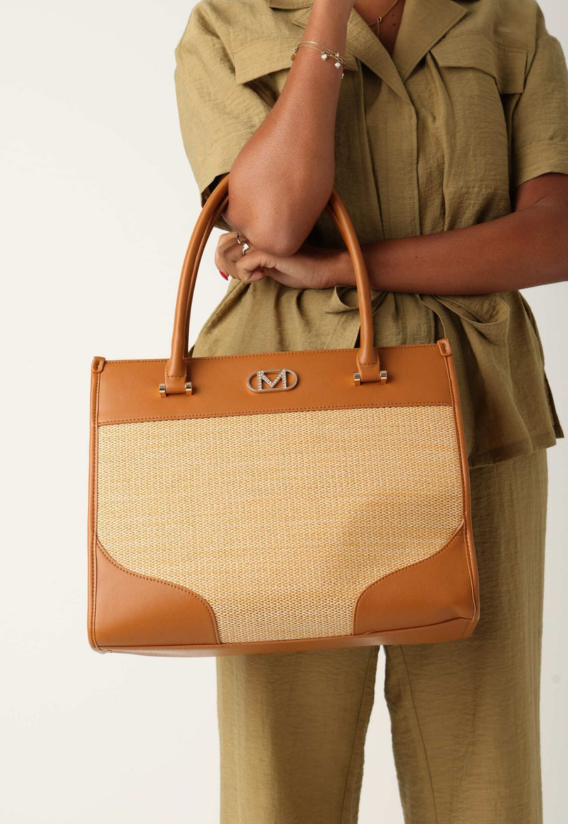 Läderhandväska i tan med flätad mittsektion, styv rektangulär form, handtag upptill och en logotypdetalj. Har både släta och strukturerade ytor.