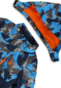 Musterjacke in Blau, Grau und Marineblau mit einer orangefarbenen Kapuze, die gefüttert ist, sowie einem orangefarbenen Reißverschluss und einem Spinnenlogo. Glattes, strapazierfähiges Material.
