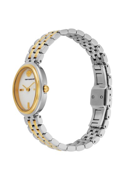 Montre-bracelet en métal argenté et doré avec cadran blanc ovale, index dorés, et logo Tory Burch sur fond blanc.