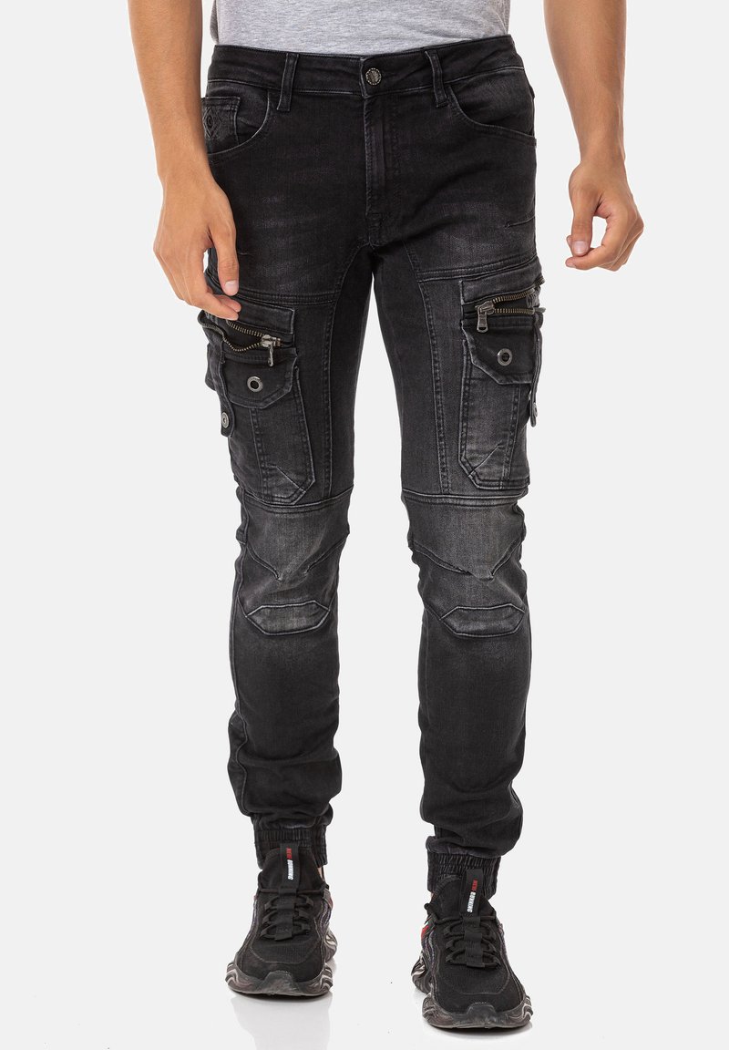 Pantalons cargo en denim noir avec plusieurs poches zippées et à rabat, bas effilés, emplacements décolorés et sections de genoux renforcées.