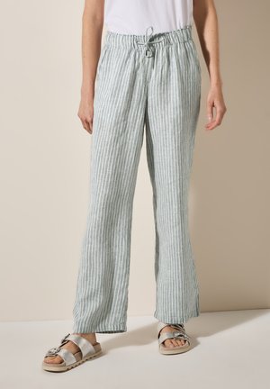 Pantaloni in lino a righe leggeri con vita regolabile; vestibilità rilassata, in toni di verde chiaro e bianco, abbinati a sandali argento.