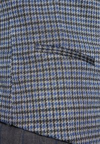 Materiał w wykrzyżowane wzory w kolorze niebieskim, czarnym i szarym. Posiada wąską kieszeń. Tekstura wydaje się gładka z usystematyzowanym wzorem.