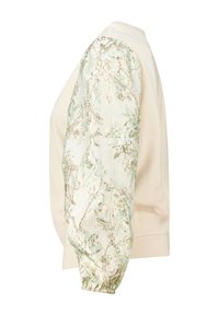 Sweatshirt de couleur crème avec une manchée texturée et brillante verte et dorée. Présente une coupe décontractée et des poignets côtelés.