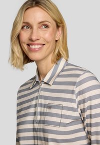 Striped polo shirt in gray and beige, featuring a zip front, classic collar, and a textured pocket with decorative accents.