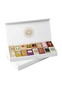 Boîte cadeau avec un extérieur blanc texturé contenant des emballages colorés de chocolats assortis, présentant divers motifs et designs complexes.