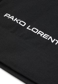 Czarna tkanina o teksturowanym splocie z wyraźnym napisem "PAKO LORENT".