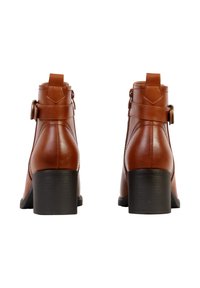 Paire de bottines en cuir marron avec talons carrés noirs, vue de dos, fond blanc.