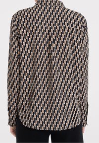 Camicia a maniche lunghe con un motivo a onde nero e beige, realizzata in un tessuto liscio. Presenta un colletto standard e polsini con bottoni.