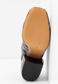Semelle d'une botte à motif zébré avec un fond en cuir marron clair et un talon bloc noir, taille 37, présentée sur un fond blanc.