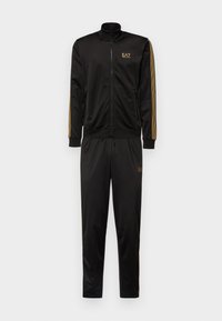 Black tracksuit made of smooth fabric. Zip-up jacket with high collar, gold logo, and gold-striped sleeves. Matching pants with elastic waistband.