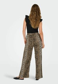 Haut noir à manches à volants, assorti à un pantalon à jambes larges avec un motif léopard aux tons beige et marron.