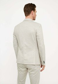 Helle graue Anzugjacke mit taillierter Passform, Reverskragen und Zweiknopfverschluss. Verfügt über zwei Seitentaschen und eine dezente Stofftextur.