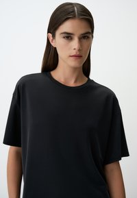 Zwarte korte mouwen t-shirt van zacht katoen. Heeft een ronde hals en een relaxte fit; gladde textuur zonder zichtbare patronen.