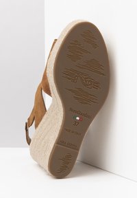 Wedge sandal with a brown suede upper, woven jute platform, and rubber outsole. Features branding and size marking on the sole.