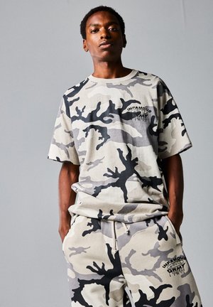 Camiseta de camuflaje gris y sudaderas a juego, con un ajuste relajado y detalles en negro, con el logo "INFAMOUS" en el pecho y el muslo.