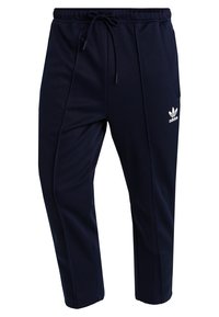 Námořnické modré sportovní kalhoty vyrobené z hladkého materiálu, s elastickým pasem, šňůrkou na stažení a bílým logem Adidas na levém stehně.