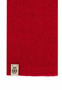 Red knitted scarf with a soft texture. Features a small fabric tag with a logo at the bottom corner.